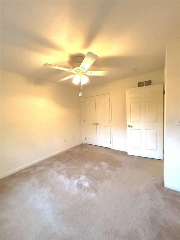 unfurnished bedroom with carpet floors, baseboards, a closet, and a ceiling fan