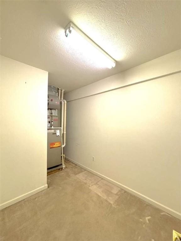 finished below grade area featuring a textured ceiling, heating unit, baseboards, and carpet