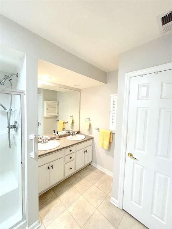 full bathroom with a stall shower, tile patterned floors, double vanity, and baseboards