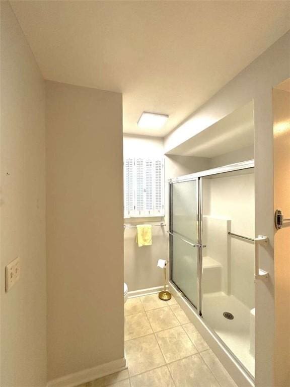 full bath featuring tile patterned floors, a shower stall, baseboards, and toilet