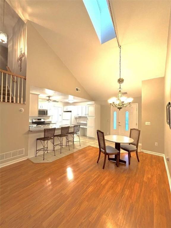 100 Westminster Dr, Ross Twp, PA 15229 - dining room with high vaulted ceiling, a chandelier, stairs, light wood-type flooring, and baseboards