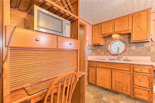 190 W Main St, Donegal Wml, PA 15628 - kitchen featuring stainless steel microwave, a sink, brown cabinetry, an ornate ceiling, and light stone finish flooring