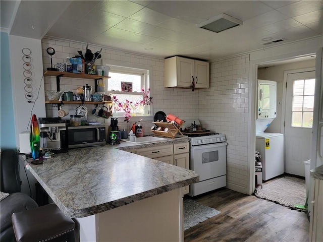 301 Main St, E Mahoning/Marion Ctr, PA 15759 - kitchen featuring white range with gas cooktop, a sink, estacked washer and dryer, stainless steel microwave, and a peninsula