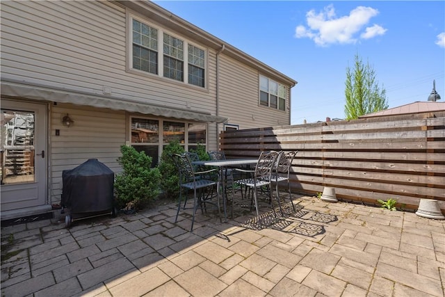 view of patio featuring fence, outdoor dining space, and grilling area