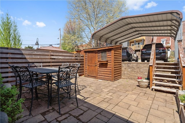 view of patio with fence, outdoor dining space, and a detached carport