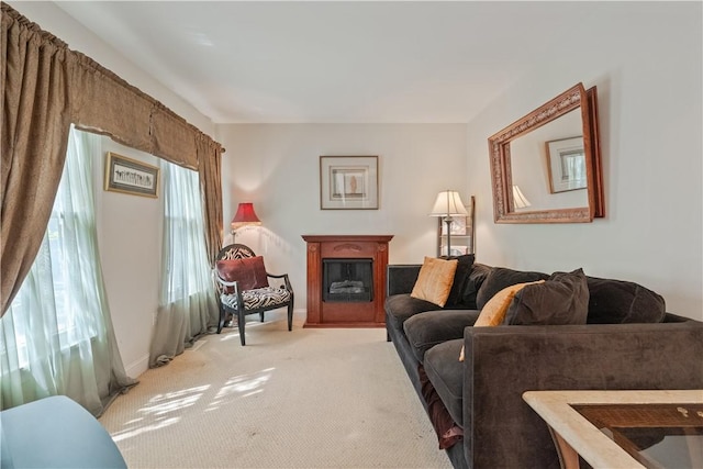 living area featuring light carpet, a glass covered fireplace, and baseboards