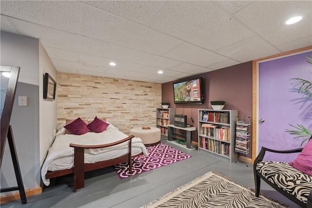 living area with concrete flooring, a drop ceiling, baseboards, and recessed lighting