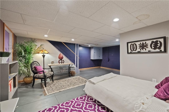bedroom featuring a paneled ceiling, finished concrete floors, baseboards, and recessed lighting