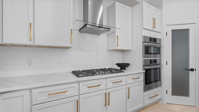130 Prospect St, Mt Washington, PA 15211 - kitchen featuring wall chimney range hood, stainless steel appliances, white cabinetry, and light stone counters
