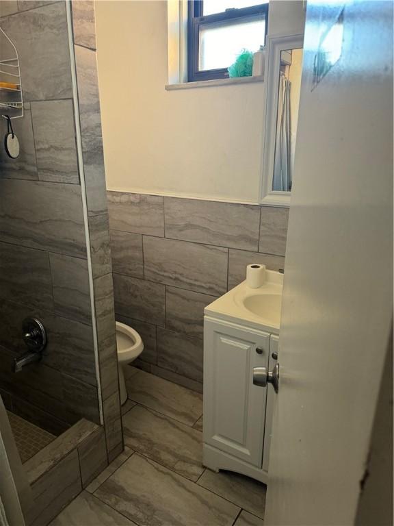 1215 Schimmer St, Brighton Heights, PA 15212 - bathroom with tile walls, a tile shower, marble finish flooring, vanity, and toilet