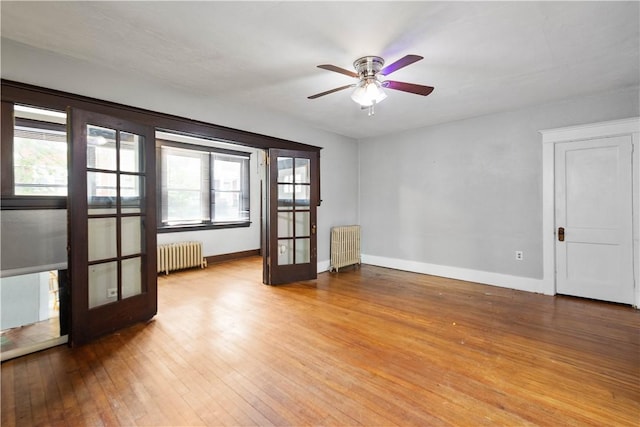 spare room featuring radiator heating unit, plenty of natural light, and wood-type flooring