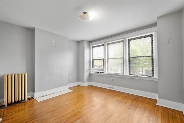 spare room with radiator heating unit, hardwood / wood-style floors, and baseboards