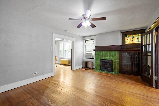 unfurnished living room with radiator heating unit, baseboards, wood-type flooring, and a textured ceiling