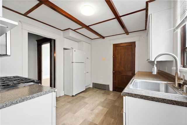 kitchen with freestanding refrigerator, a sink, white cabinetry, and dark countertops
