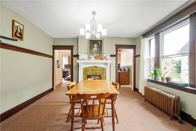 dining space featuring radiator, carpet floors, a tile fireplace, a chandelier, and a textured ceiling
