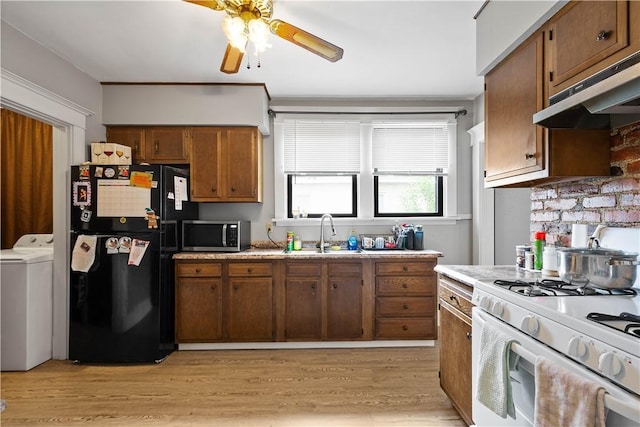kitchen featuring black fridge, washer / dryer, white range with gas cooktop, a sink, and stainless steel microwave