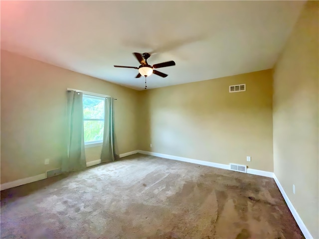 carpeted spare room featuring ceiling fan and baseboards