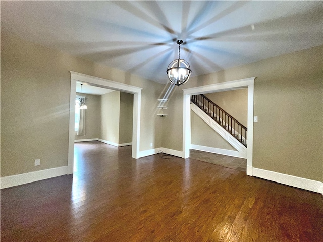 unfurnished dining area featuring a chandelier, dark wood finished floors, stairway, and baseboards