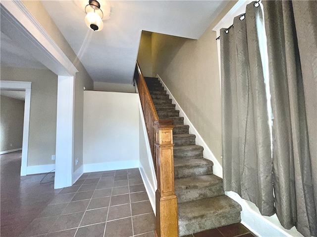 stairway with baseboards and tile patterned flooring