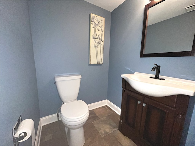 bathroom featuring toilet, vanity, and baseboards