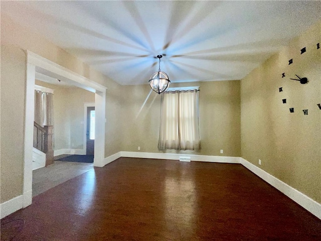 spare room featuring wood finished floors, baseboards, and a chandelier