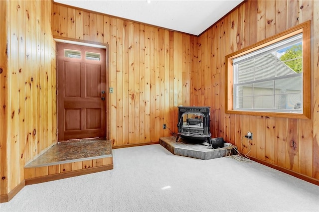 431 Mount Morris Rd, Kirby/Mtmorris, PA 15349 - unfurnished room featuring a wood stove, carpet, wooden walls, and baseboards