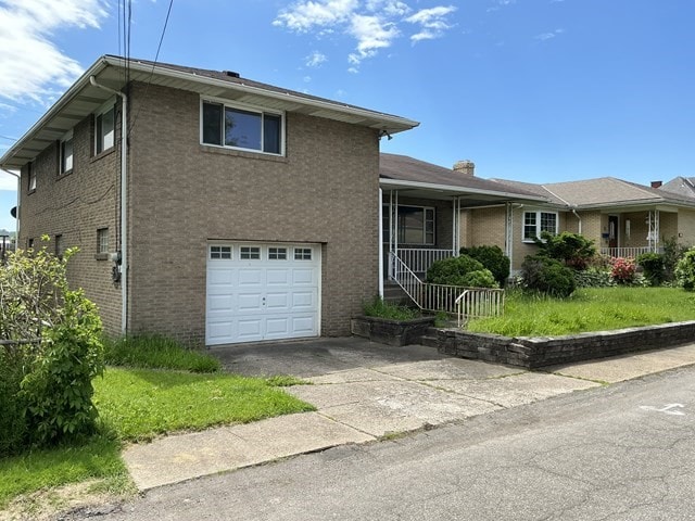 13 Schoen St, Mckees Rocks, PA 15136 - view of front of home with a garage, brick siding, asphalt driveway, and covered porch