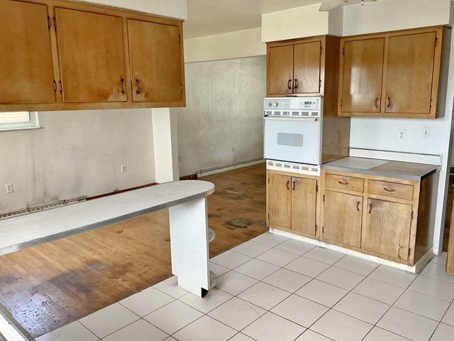 13 Schoen St, Mckees Rocks, PA 15136 - kitchen with white oven, brown cabinetry, light countertops, and light tile patterned floors