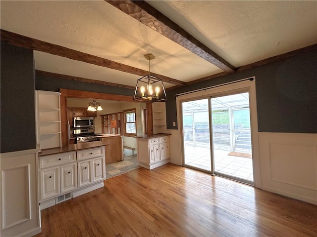 508 Woodside Rd, Forest Hills Boro, PA 15221 - kitchen with a chandelier, a peninsula, appliances with stainless steel finishes, beam ceiling, and light wood-type flooring