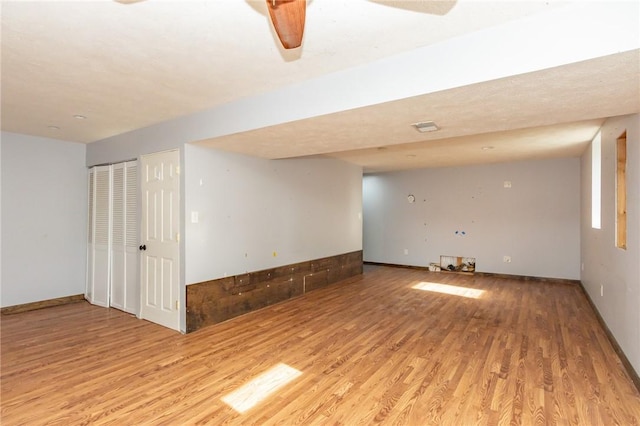 empty room with light wood-style flooring, a ceiling fan, and baseboards
