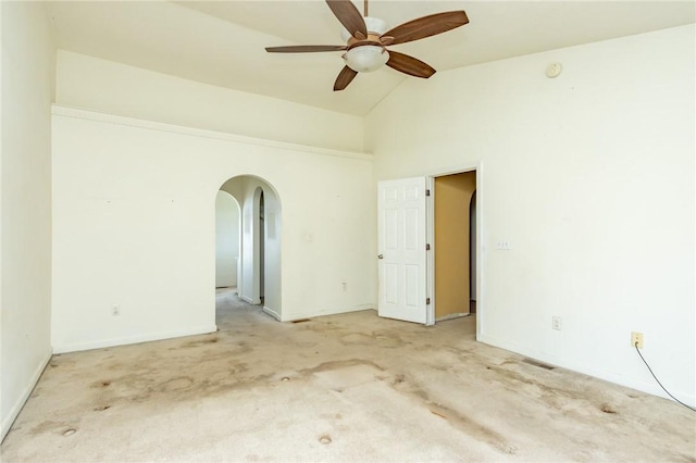 spare room featuring arched walkways, lofted ceiling, a ceiling fan, light carpet, and baseboards
