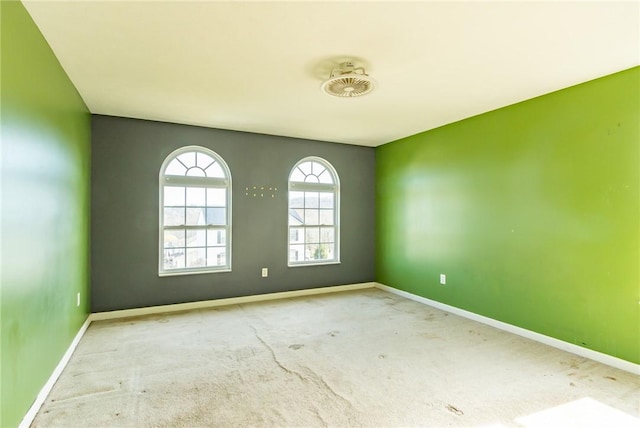 carpeted spare room featuring baseboards
