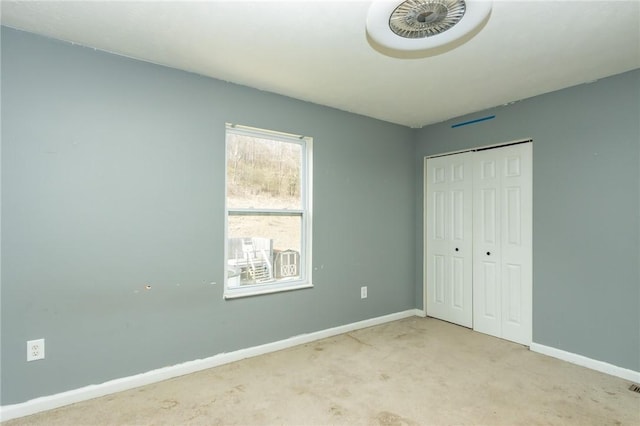 unfurnished bedroom with baseboards, carpet flooring, and a closet