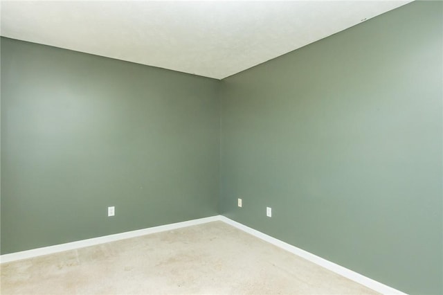 spare room featuring baseboards and light colored carpet