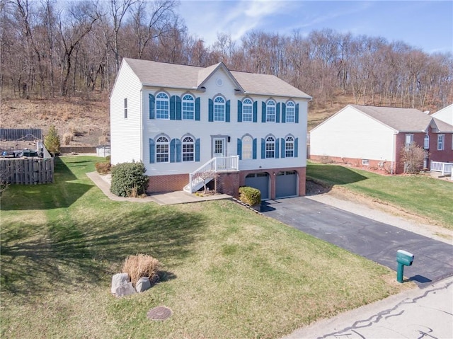view of front of property featuring an attached garage, asphalt driveway, a front lawn, brick siding, and a shingled roof