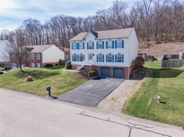 view of front of house featuring an attached garage, asphalt driveway, a front yard, and brick siding