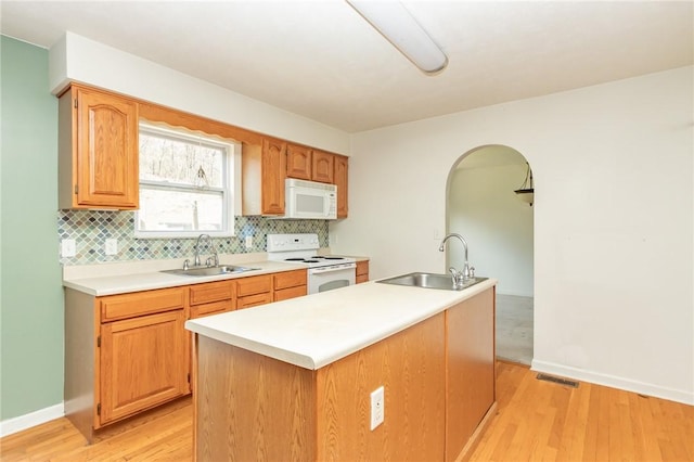 kitchen featuring white appliances, a sink, and light wood-style floors
