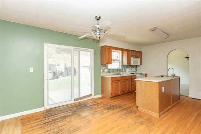 kitchen featuring white appliances, a sink, light countertops, and light wood-style floors