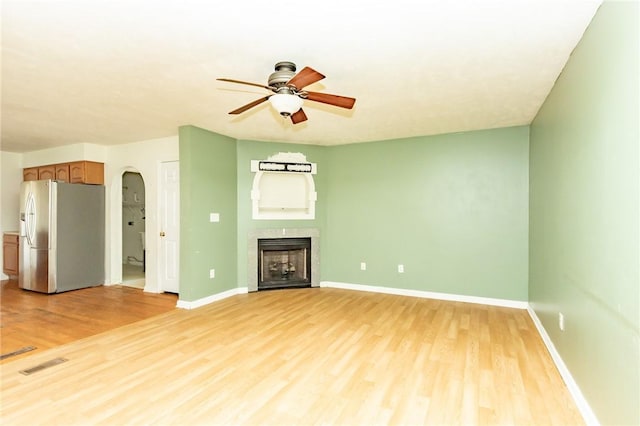 unfurnished living room with light wood-style floors, a ceiling fan, baseboards, and a fireplace