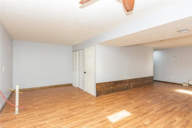 empty room featuring wood finished floors, a ceiling fan, and baseboards