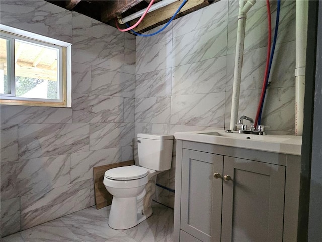 bathroom featuring marble look tiles, tile walls, vanity, and toilet