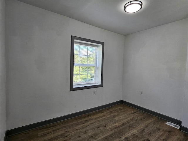empty room featuring dark wood finished floors and baseboards