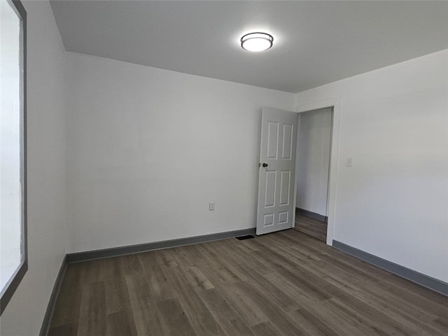 spare room featuring dark wood-type flooring and baseboards