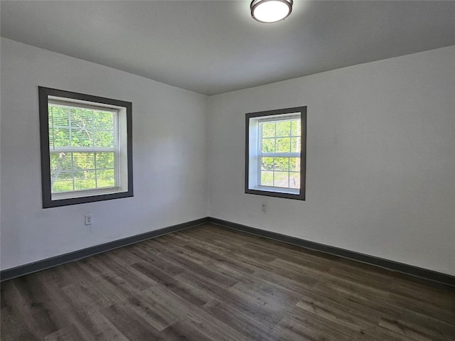 spare room featuring dark wood-style floors and baseboards