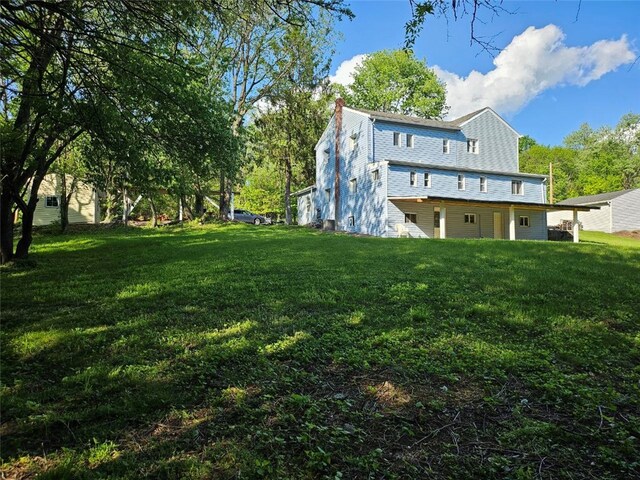 back of property with a chimney and a yard