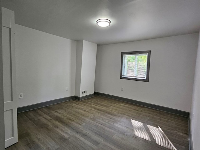 spare room with dark wood-type flooring and baseboards