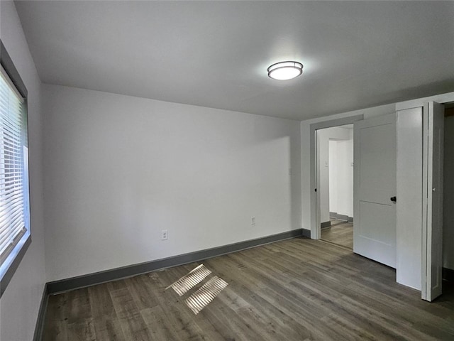 unfurnished bedroom featuring dark wood finished floors, baseboards, and multiple windows
