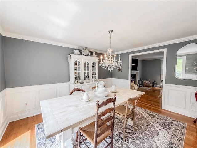 2388 Mill Grove Rd, Upper St Clair, PA 15241 - dining space with a chandelier, wainscoting, a decorative wall, light wood-style floors, and ornamental molding