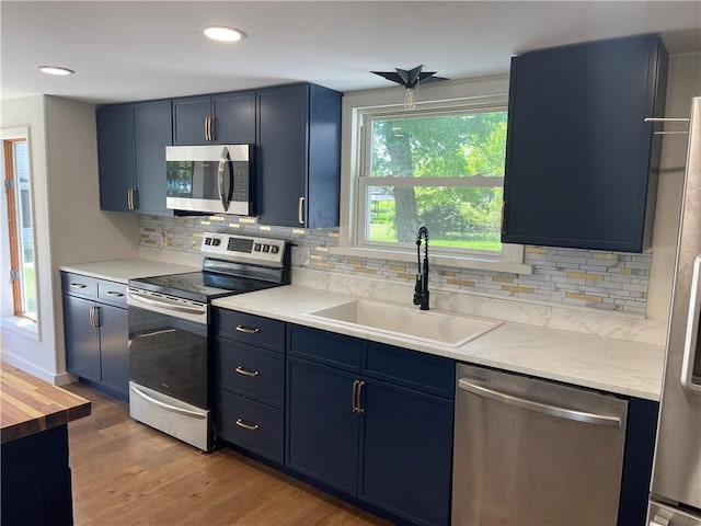 218 S Mercer, Linesville Boro, PA 16424 - kitchen featuring stainless steel appliances, a sink, blue cabinetry, light wood-type flooring, and backsplash