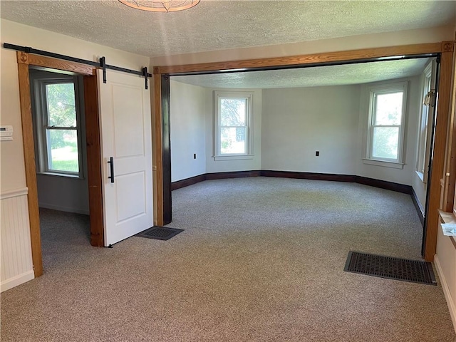 218 S Mercer, Linesville Boro, PA 16424 - carpeted empty room featuring a barn door, a textured ceiling, baseboards, and healthy amount of natural light